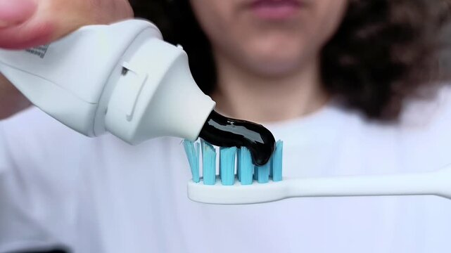 The process of applying black toothpaste to a toothbrush