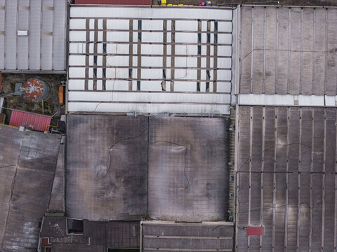Aerial view of industrial rooftops with weathered textures and geometric patterns in Leccio, Tuscany, Italy.