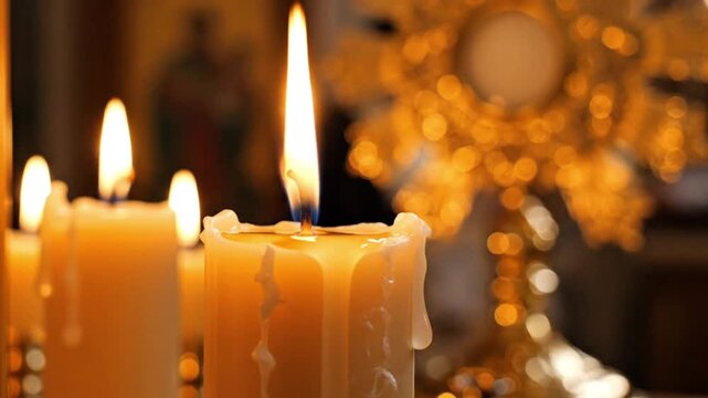Close-up of burning candles in a church with a golden monstrance in bokeh background, symbolizing religious adoration and spiritual prayer.