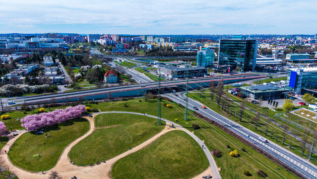 Aerial view of vibrant green parkland contrasting with the sleek, modern architecture and winding roads, a harmonious blend of nature and urban design, Prague, Prague, Czechia.