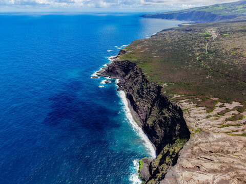 Aerial view of the rugged coastline meets the deep blue sea, a stark contrast of textures and tones, Capelo, Acores, Portugal.