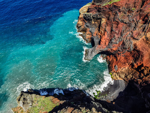 Aerial view of the dramatic contrast between the dark volcanic rock and the turquoise sea, Capelo, Acores, Portugal.