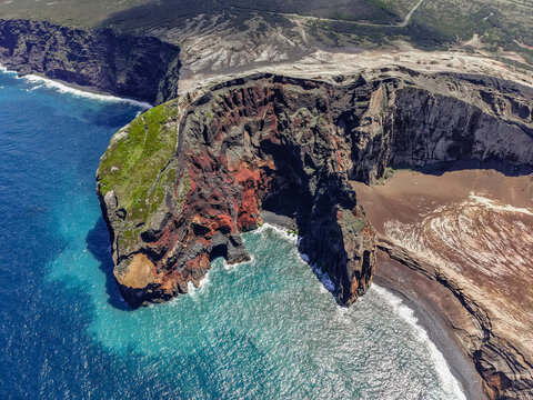 Aerial view of the dramatic Capelinhos Volcano's contrasting red and black rock formations meeting the deep blue sea, Capelo, Acores, Portugal.