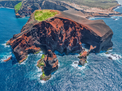 Aerial view of the dramatic Capelinhos Volcano, where rust-colored cliffs meet the deep blue sea, a stunning contrast of volcanic rock and ocean waves, Capelo, Acores, Portugal.