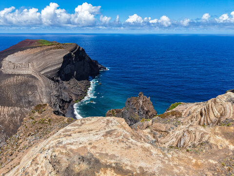 Aerial view of the stark, volcanic landscape contrasting with the azure sea and the dramatic cliffs of Capelinhos Volcano, Capelo, Acores, Portugal.