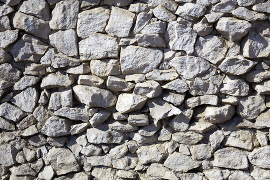 Natural stone wall showcases varied textures and colors in an outdoor setting during daylight hours