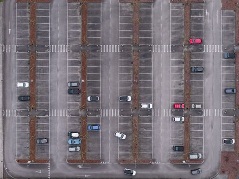 Aerial view of a large parking lot with various parked cars and white pedestrian crossings on asphalt Leccio, Tuscany, Italy.