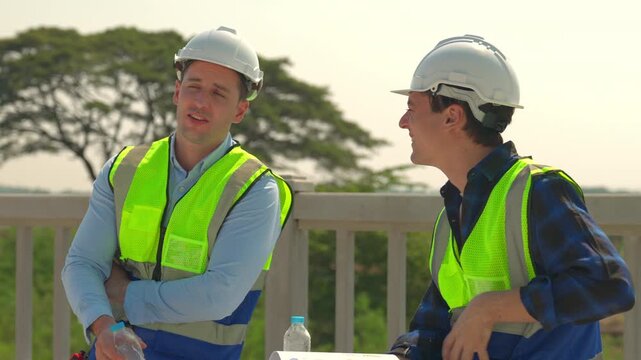 Construction worker in safety vest and hard hat discussion on outdoor site with engineer, teamwork, planning, safety, daylight worksite conversation