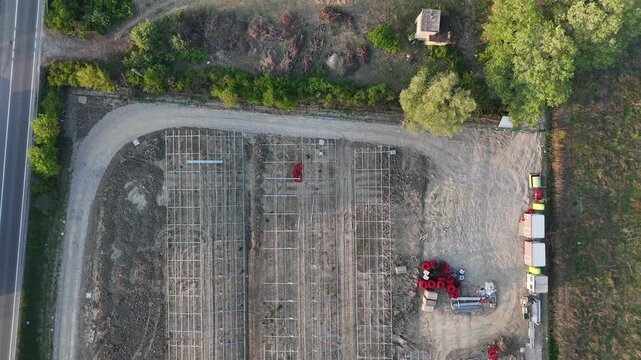 Drone footage captures the ongoing construction of a solar power plant, showcasing metal frames and machinery under the warm glow of sunset