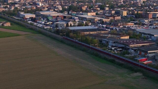 Trenitalia Frecciarossa high speed passenger train running parallel to Autostrada A1 near Fiorenzuola d Arda Piacenza Emilia Romagna Italy within Milan Bologna rail corridor, drone tracking