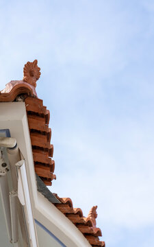 Traditional Greek roof tiles with decorative clay acroterion against blue sky