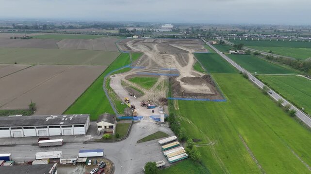 Drone footage captures ongoing earthworks and infrastructure development for a new logistics hub adjacent to agricultural land and a major road