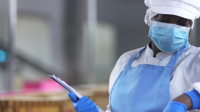 food safety researchers in lab coats discussing quality audit findings in seafood processing facility. A food safety inspector holding a clipboard while overseeing factory workers processing seafood