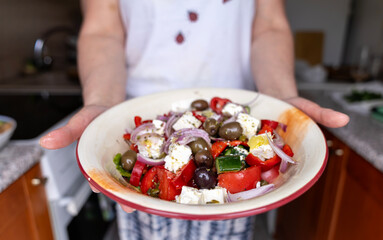 Naklejka premium Woman holding a bowl of fresh traditional Greek salad