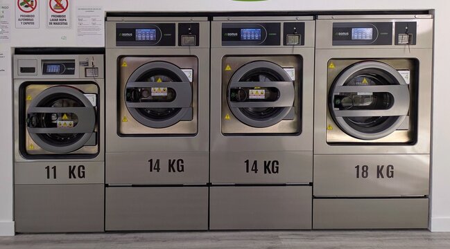 Lavander&iacute;a moderna autoservicio, con una hilera de puertas de lavadoras industriales marca Domus Laundry, en Madrid, Espa&ntilde;a, 12 de marzo de 2026