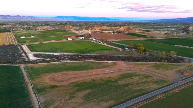 Aerial view of a patchwork of green fields meeting the desert landscape under a pastel sky, Fruita, Colorado, United States.