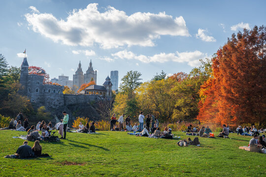 Manhattan, United States - 08 November 2025: View of people relaxing on the Great Lawn, the Belvedere Castle standing proudly against the skyline, framed by autumn foliage.