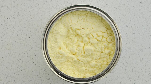 Powdered milk container with open lid, highlighting the fine texture and practicality of this essential product.