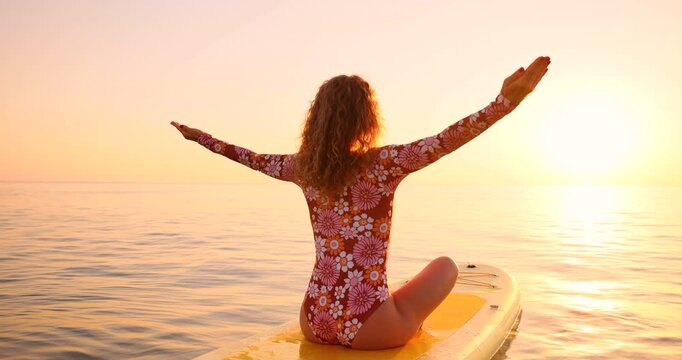 A happy young woman walking on a sup board by the sea during her summer vacation. Slow motion