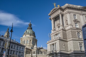 Obraz premium Dome and curved colonnade of St. Stephen's Basilica in Budapest against a bright blue sky.
