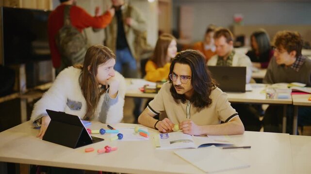 Two dedicated students concentrate on their tasks, utilizing modern tools and traditional books for education.