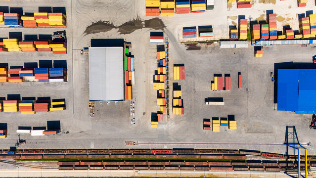 Aerial view of vibrant shipping containers stacked high, creating a colorful grid against the stark concrete, Sremska Mitrovica, Vojvodina, Serbia.