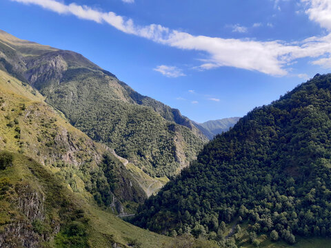 Dramatic mountain valley with convergent slopes and a long cloud in the Caucasus