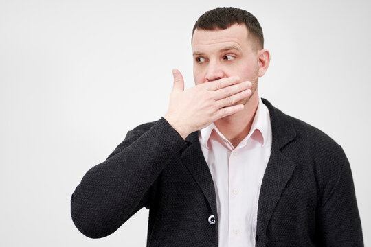 portrait of man with hand over his mouth looking aside, stunned and speechless concept