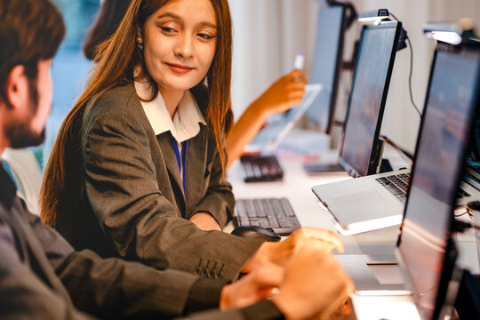 Smiling DevSecOps engineer engaging in a productive discussion with a coworker. Professional multiethnic IT squad working on cloud native security protocols in a bright office environment.