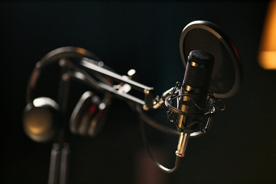 Close up of studio microphone with pop filter and headphones supporting podcast recording, livestream production, audio branding, content marketing, copy space