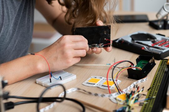 Young person working on electronic project with breadboard and wires