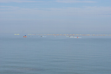 rowing competition athletes training on calm sea water surface blue sky background professional rowers in boats racing at sunset with copy space for banner design concept of sports, recreation © Lana Pietukhova