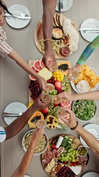 People, hands or feast with cheers above for healthy meal, charcuterie board or social gathering. Top view, group or friends with wine glasses, fruit or food for event or toast together at table