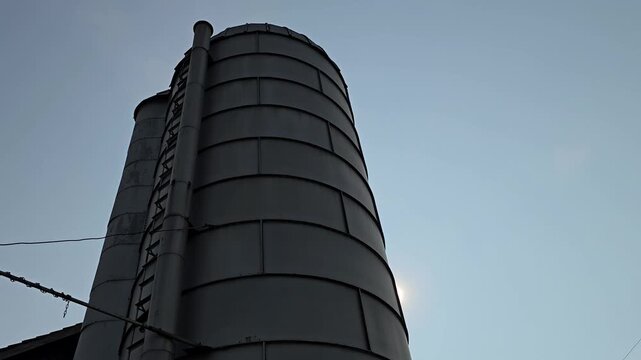 Farm grain silo with sun peering out from the side horizontal video