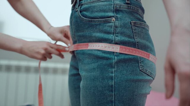 Measuring hip circumference with measuring tape of girl in jeans