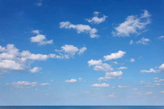 Blue sky with small white clouds over the sea
