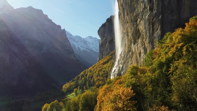 A stunning landscape showcases the stabbach falls cascading down a sheer cliff face, surrounded by vibrant autumn foliage and towering mountains. high-quality professional detailed modern