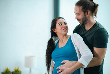 Naklejka premium Father's Day Concept, pregnant couple embracing in home, smiling at each other, romantic maternity moment