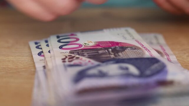 Horizontal 4K video close up. Man counts one hundred lari bill on wood table close up. Purple lilac paper banknote 100 GEL. Georgian cash money. Concept of budget, pay tax, loan, wages, bribe, debt