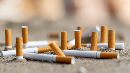 Obraz premium Pile of discarded cigarettes scattered on sandy beach surface