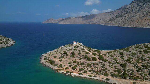 Aerial view of Panormitis Bay with traditional windmill and blue sea, Symi island