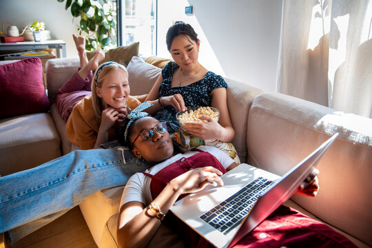 Three friends watching a movie on a laptop at home