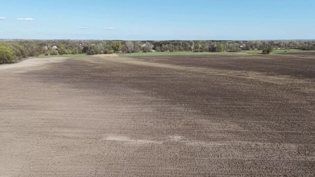 High angle drone view of vast agricultural field with signs of soil erosion. Dark fertile earth and light eroded patches on rolling hills in countryside. Environmental disaster and soil degradation