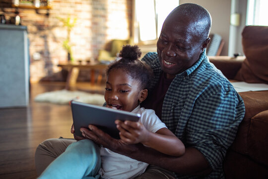Grandfather and granddaughter using tablet at home