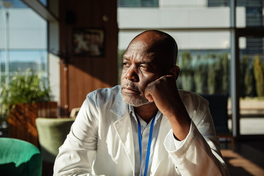 Thoughtful senior doctor resting in hospital lounge