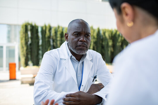 Doctor consulting with colleague outdoors at hospital