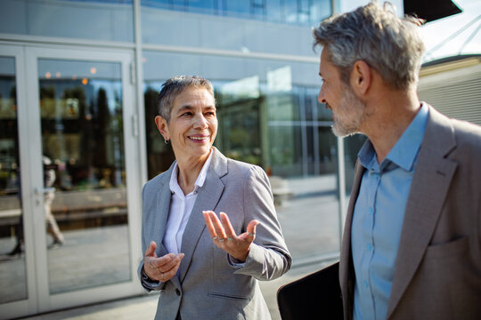 Two senior business professionals talking outside office