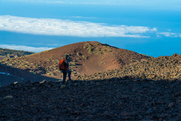 Obraz premium A tourist with a backpack is watching the scenery in Teide National Park.