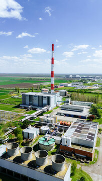 Aerial view of a towering red and white striped chimney rising above industrial buildings, contrasting against the serene blue sky, Zrenjanin, Vojvodina, Serbia.