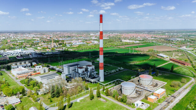 Aerial view of the towering chimney with red and white stripes rising above the industrial complex, contrasting against the blue sky, Zrenjanin, Vojvodina, Serbia.